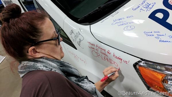 the author with a red sharpie writing on a white SUV