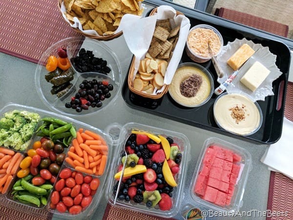 a spread of vegetables, fruit, olives, cheese and crackers on red placemats