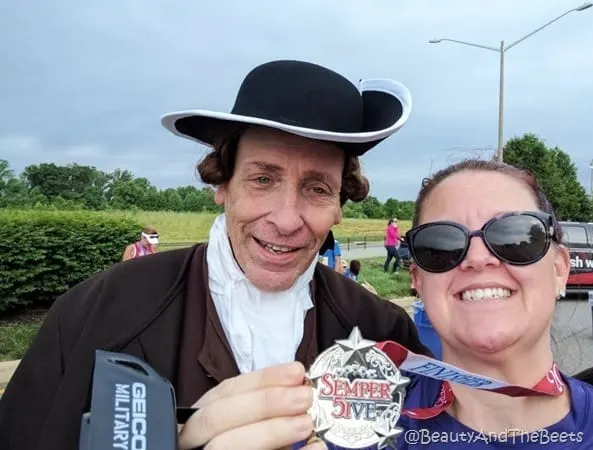 the author holding up the Semper Five Miler medal with a man dressed as the Fredericksburg Town Crier