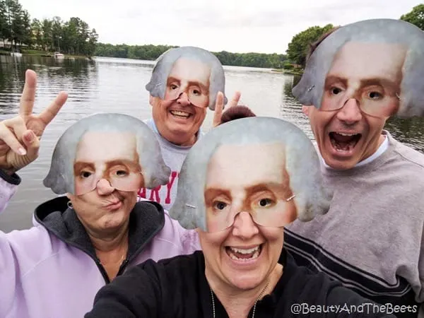 four people wearing half masks of George Washington on a lake with some trees