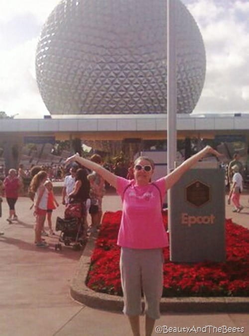 The author in a pink shirt posing big in front the Spaceship Earth ball at Epcot