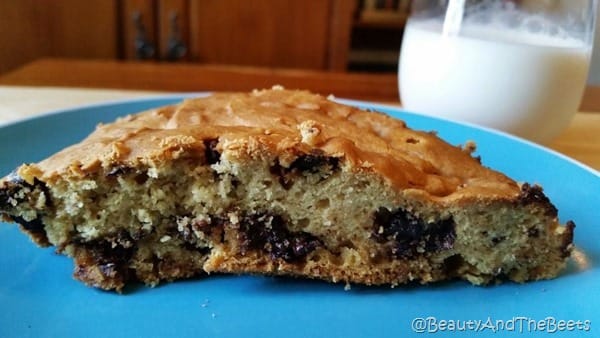 Slice of Vegan Chocolate Chip Breakfast Cake on a blue plate with a glass of white milk in the background