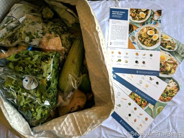 A box of bagged ingredients alongside of a grouping of recipe cards