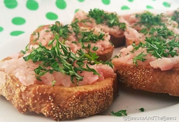 think crostini bread with braised pink radish on white plate with a green polka dot background