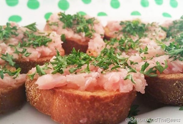 crostini bread topped with braised pink radish and parsley on a white plate
