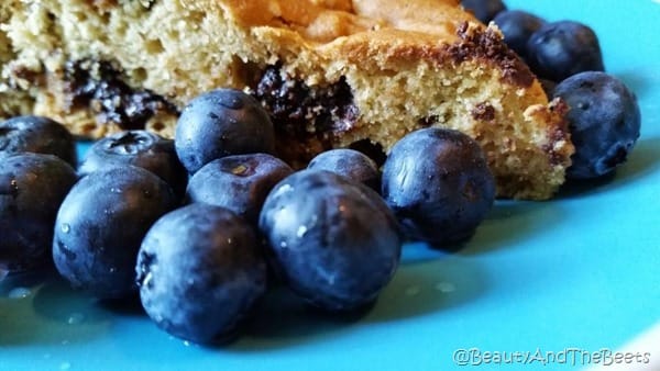 a slice of Vegan chocolate chip breakfast cake surrounded by bright blueberries on a blue plate