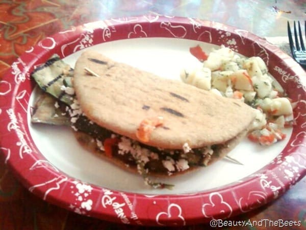 a pita sandwich with eggplant and feat cheese on a white plate with a red border