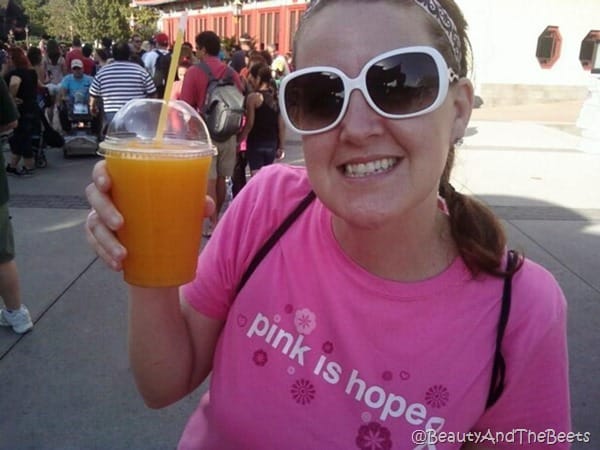 the author in a pink tee shirt holding a mango slushie