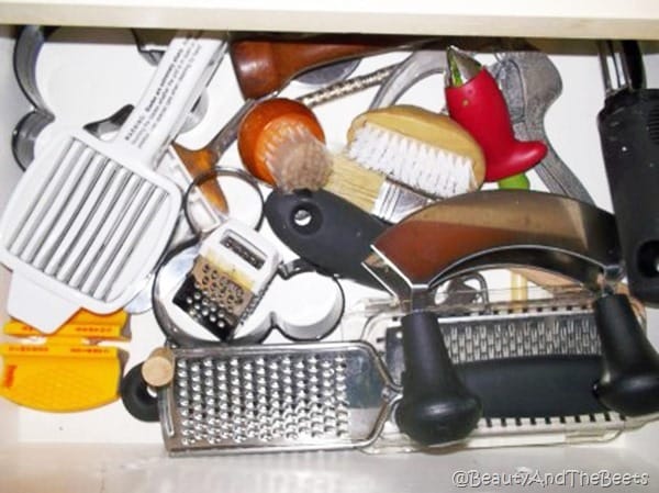 a drawer open filled with kitchen gadgets including potato scrubbers egg rings and mini graters