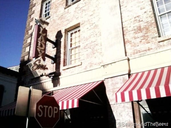 a red brick building with red and white striped awning behind a stop sign