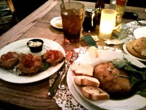 a table full of food on plates with a lit candle and a cup of iced tea