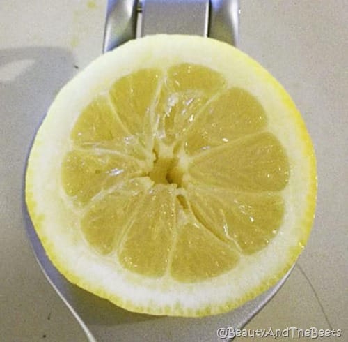 a lemon half with a white rind on a metal juicer on a white background