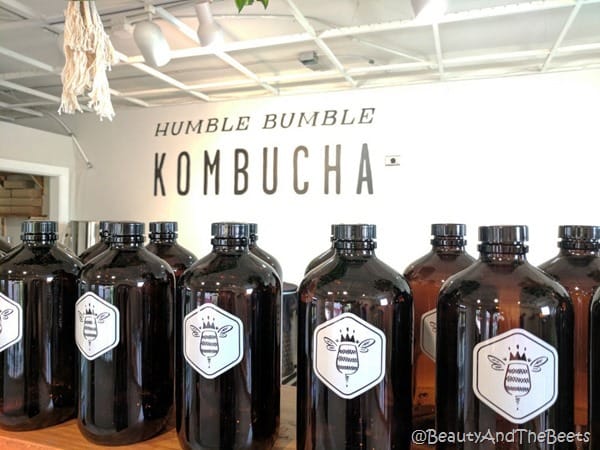 a row of brown growlers on a shelf with a white wall in the background