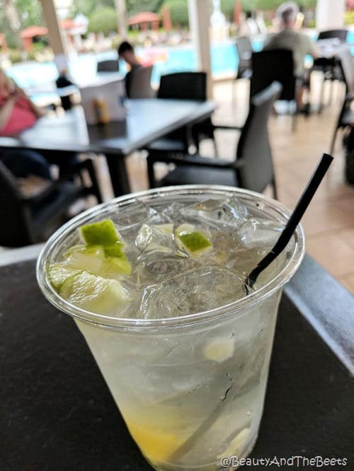 a plastic cup of tonic and lemon with ice on a table by a pool