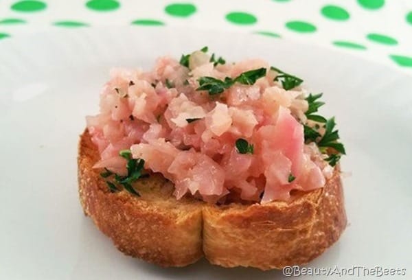single crostini bread topped with braised radish on a white plate