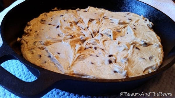 A cast iron pan filled with raw Vegan Chocolate Chip Breakfast cake batter on a blue placemat