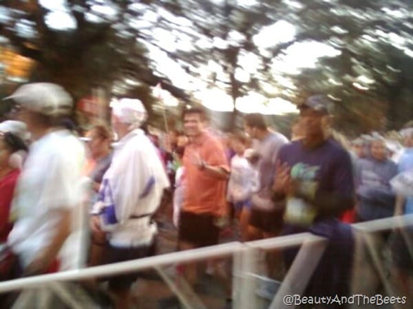 Mr Beet waving to the camera in a blurred picture of runners starting the marathon