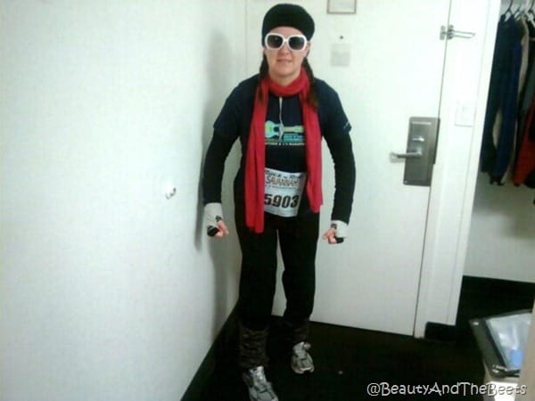 the author with a layer of hats, mittens and scarves standing by door flexing her muscles 