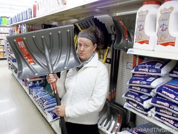 the author looking puzzled holding a big silver snow shovel in the aisle of a market