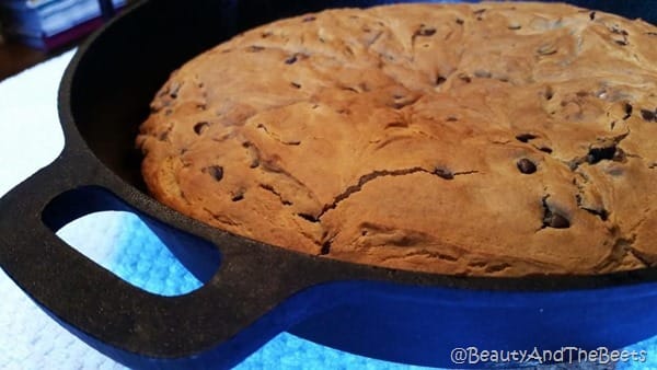 A baked Vegan chocolate chip breakfast cake in a cast iron pan on a blue placemat