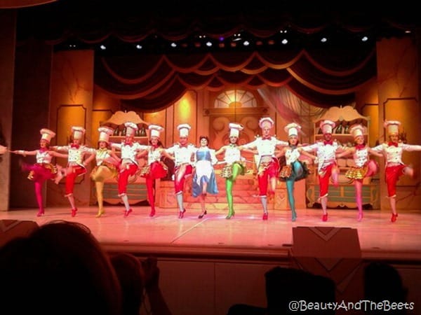 a colorful kickline of dancers and Belle on stage