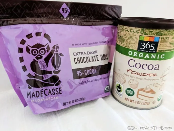 a purple bag of dark chocolate discs and a can of Whole Foods Organic cocoa