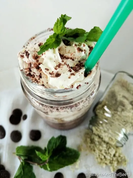 Midnight Mint Mocha Frappuccino copycat Beauty and the Beets a mason jar filled with a midnight mint mocha frappuccino, whipped cream and a mint leaf with a green straw on a white tablecloth