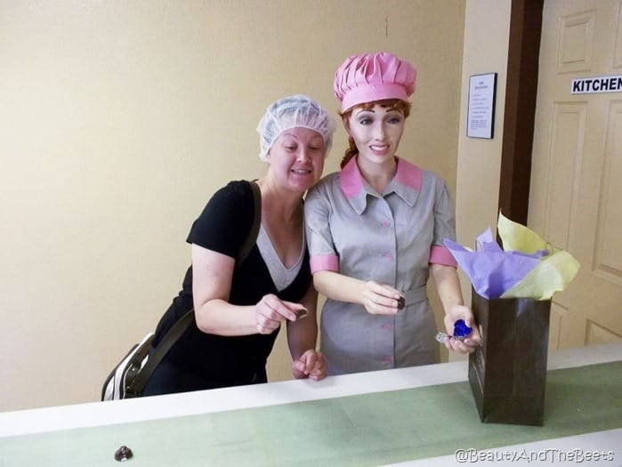 the author in a hairnet standing next to Lucille Ball statue on a chocolate belt line