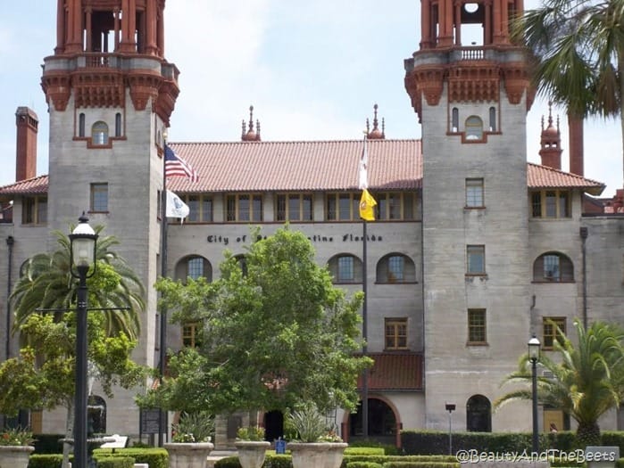 a spanish style building with two adjacent towers and palm trees