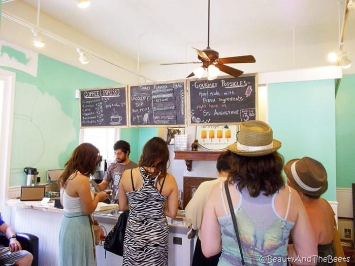 a line of customers in the Hyppo with the popsicle menu overhead and light green walls