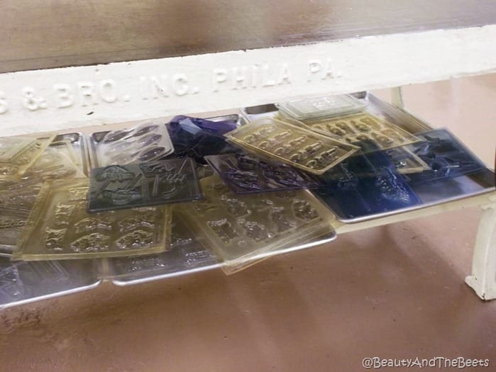 a shelf of transparent chocolate molds on an industrail white iron table