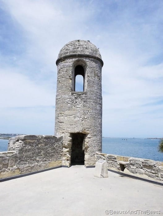 a stone tower with a lookout with the sea in the background and a blue sky