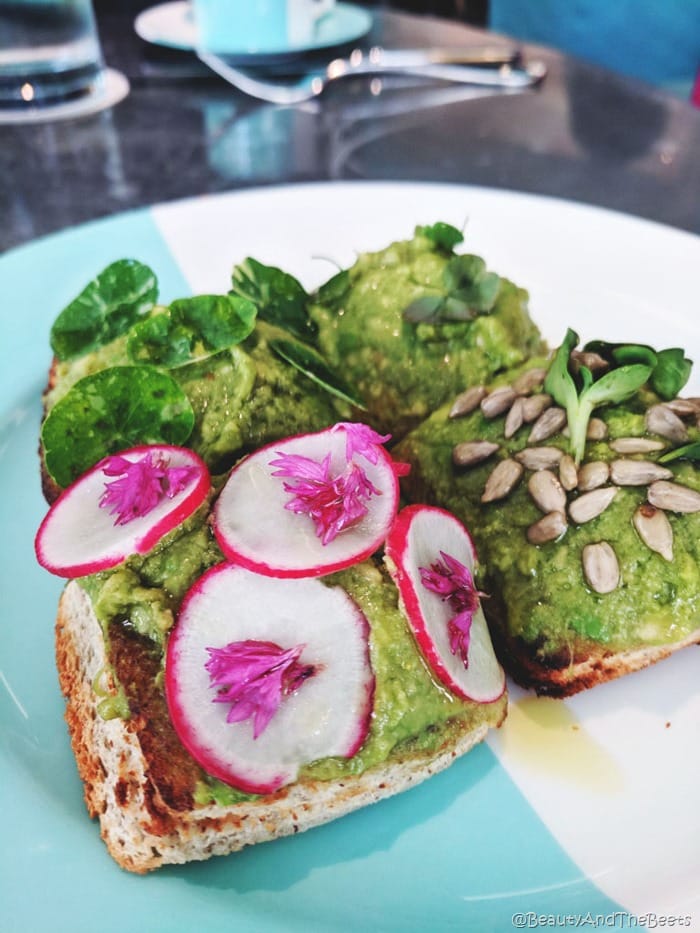 Breakfast at Tiffanys Blue Box Cafe reservations four slices of toast topped with avocado, radish, sunflower seeds on a Tiffany Blue plate