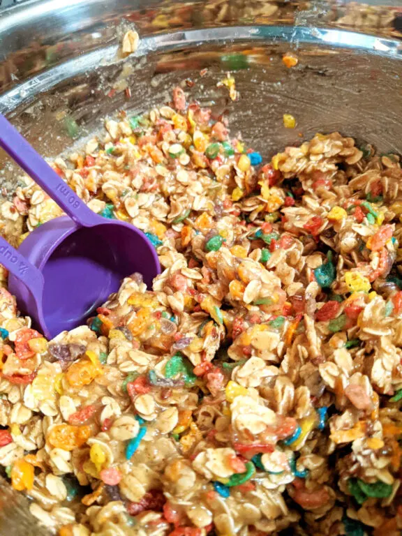 A silver mixing bowl filled with raw Fruity Pebbles cookie dough batter