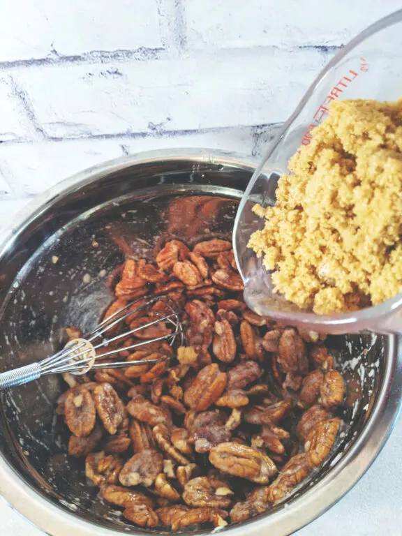 Vegan Candied Pecans brown sugar bing poured into bowl with browned pecans