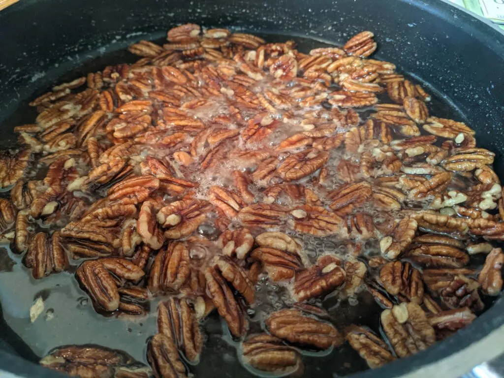 Vegan Candied Pecnas boiling in skillet over stovetop